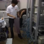 Three IT technician is tidying up the messy cables in a server room