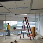 A man standing in a under renovation office with a ladder