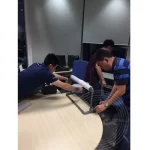 Three workers are wrapping the office appliances using the stretch film