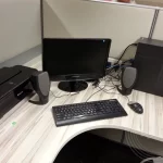 A computer with a keyboard, speakers, printer and CPU on the desk