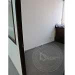 A room with a white wall, window and some wires exposed on the floor