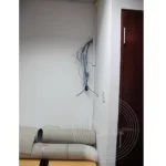 A wall with exposed wires protruding near the corner.