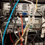 The back of the computer server with some black, orange and blue wires plugging on it