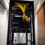 A computer server on the rack with a bunch of yellow fibre cabling