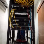A computer server on the rack with a bunch of yellow fibre cabling
