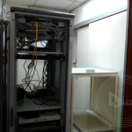 A computer server rack with wires and a shelf